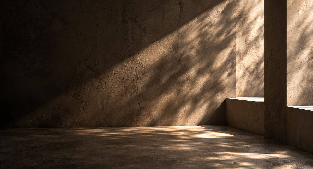 Raking daylight across a warm plaster wall and concrete step